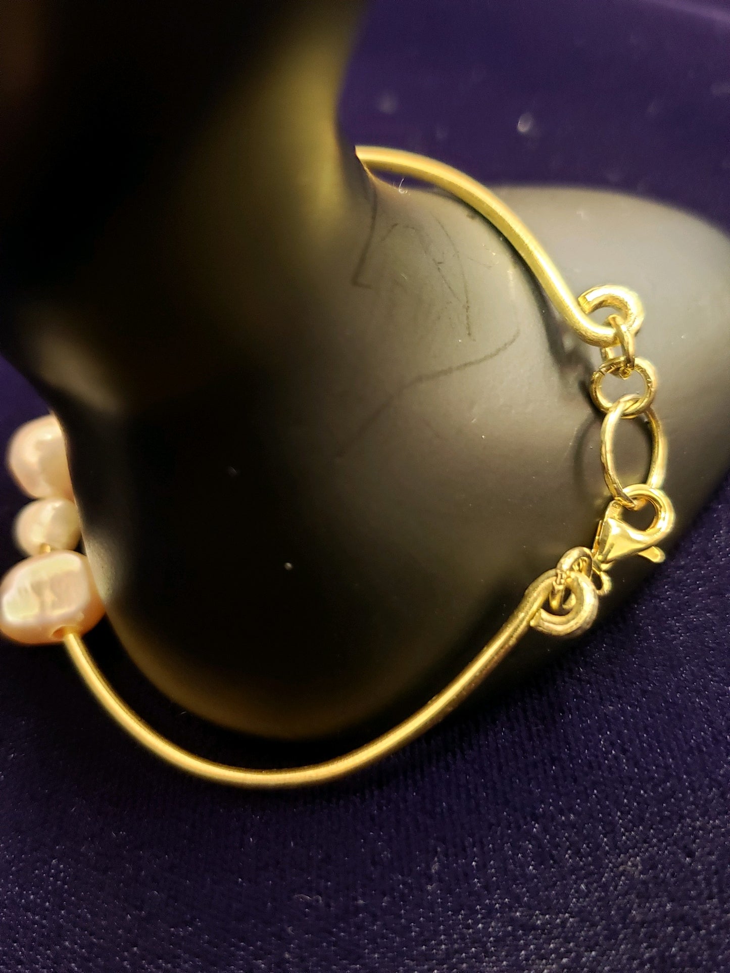 Gold bracelet with pearls on a dark background