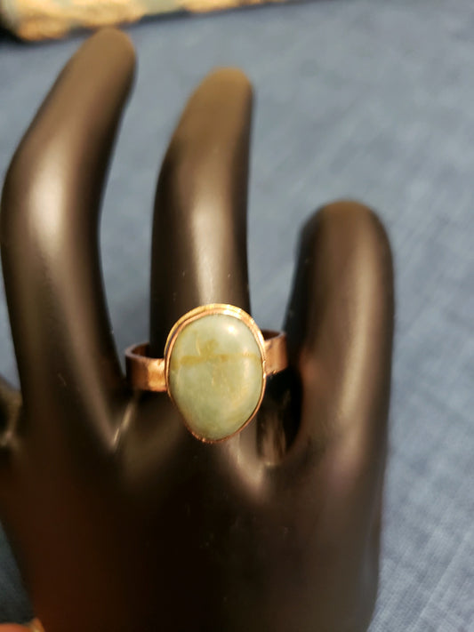 Ring with a large stone on a mannequin hand against a dark background