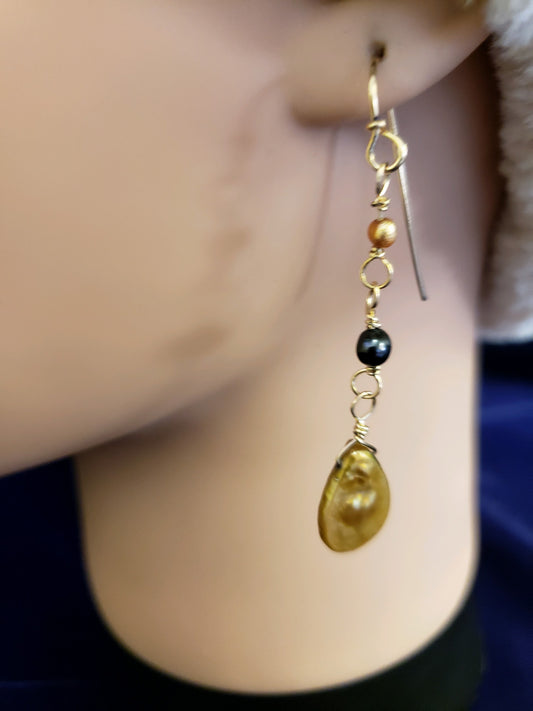 Close-up of an earring with beads and a teardrop-shaped gemstone worn on an ear.