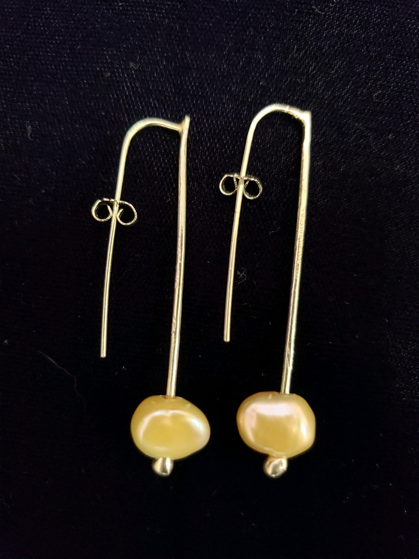 Pair of gold earrings with yellow beads on a black background