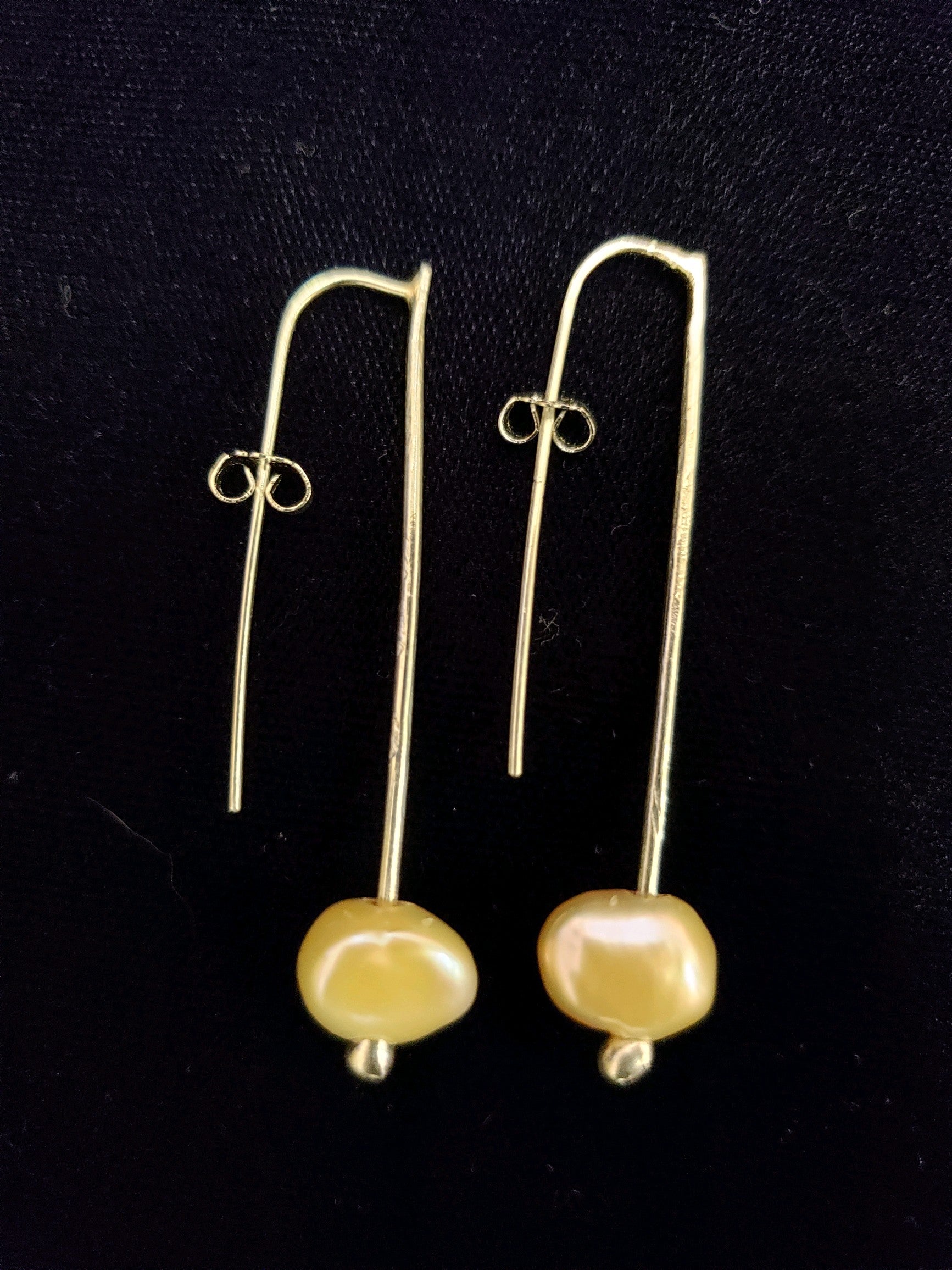 Pair of gold earrings with yellow beads on a black background
