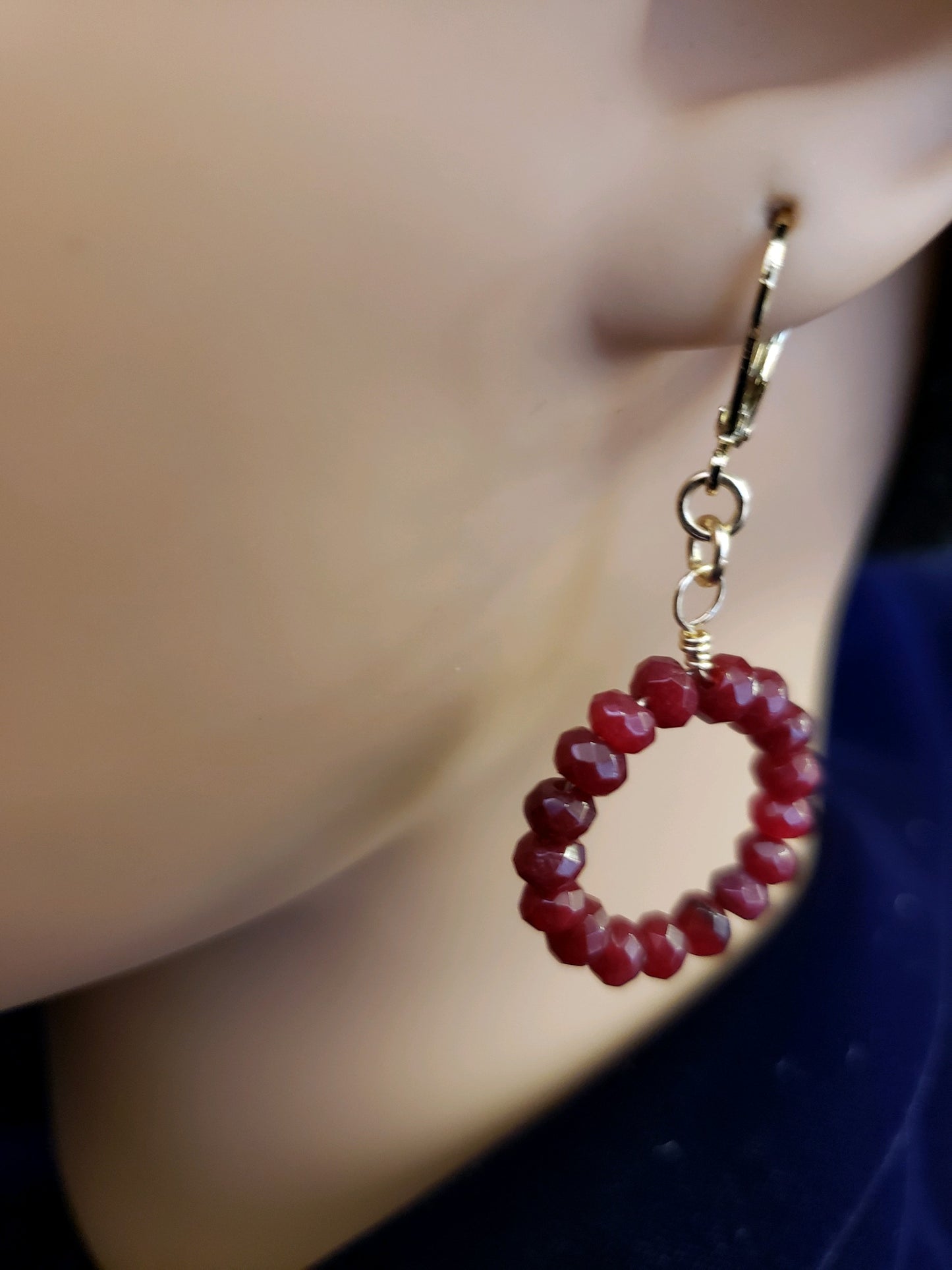 Close-up of a red beaded hoop earring . 