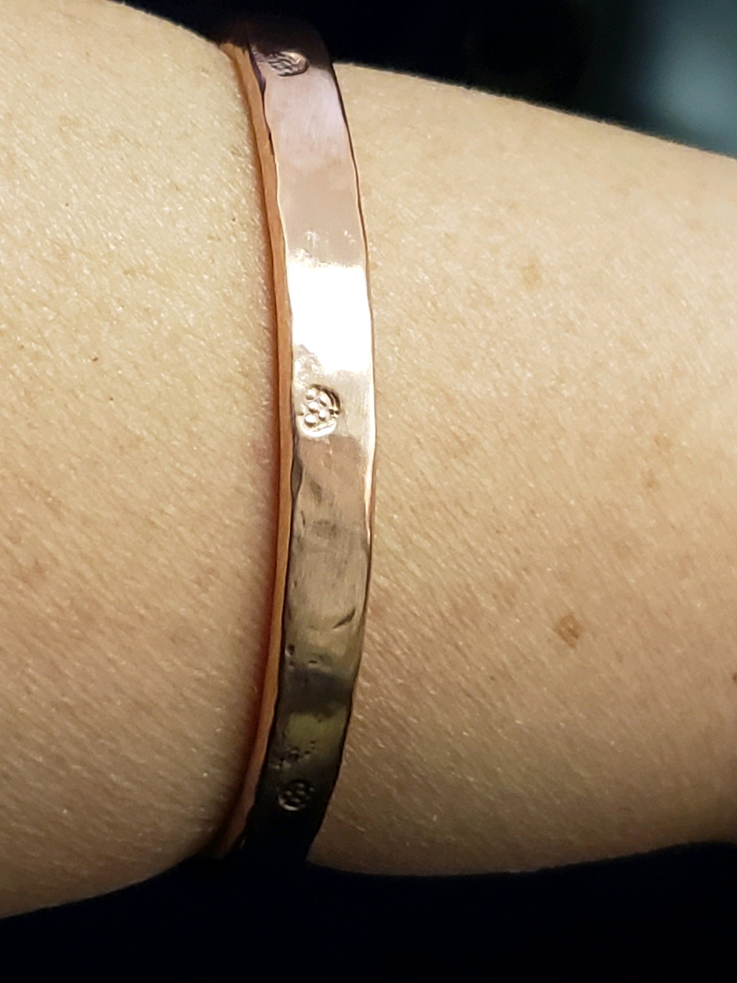 Rose copper bracelet on a wrist with a dark background