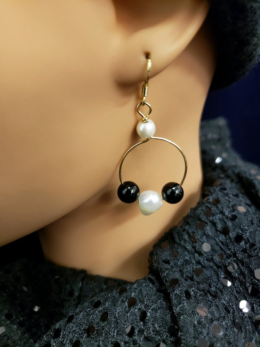 Earring with gold hoop, black bead, and pearl. 