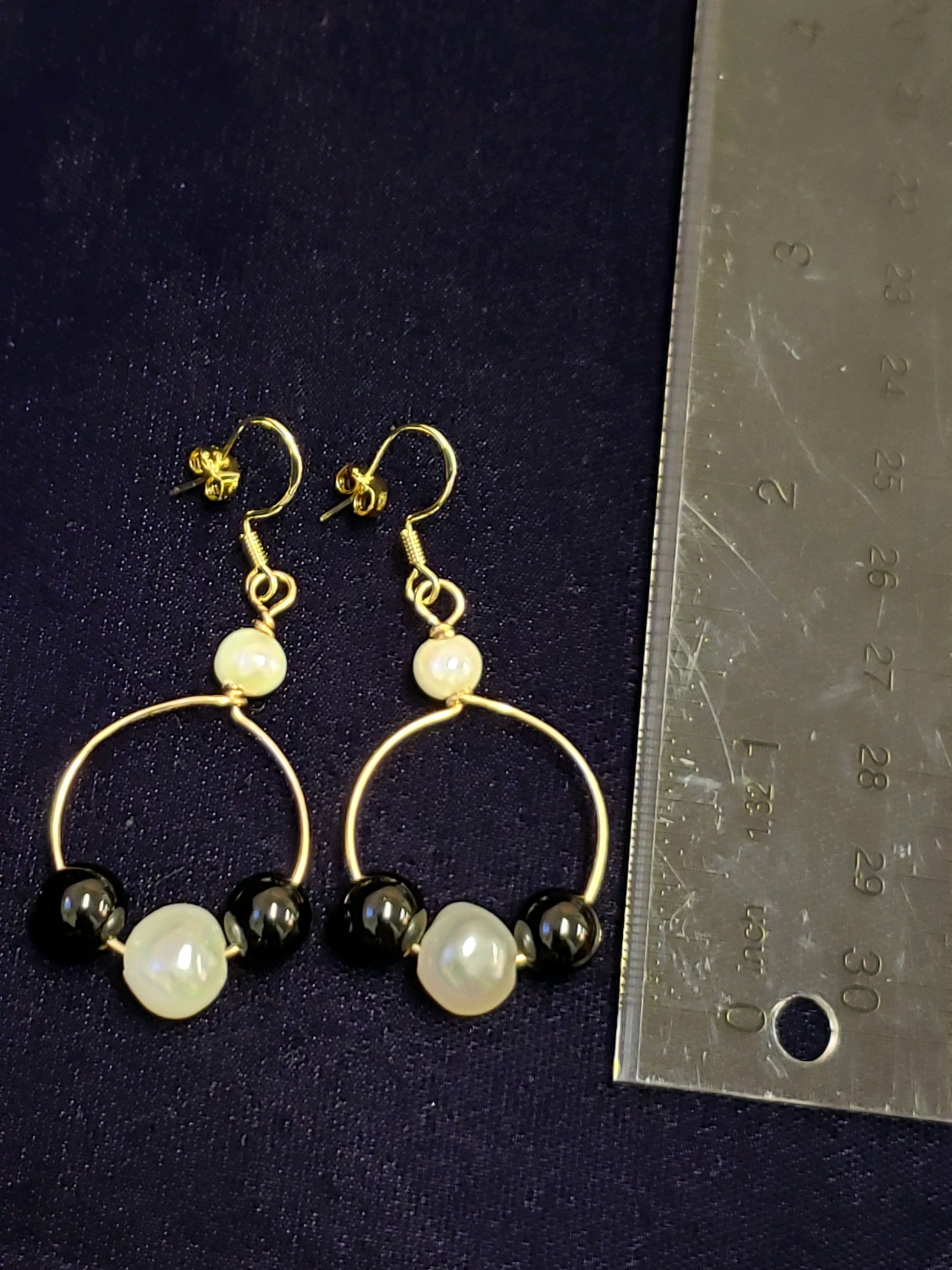 Gold hoop earrings with pearls and black beads.