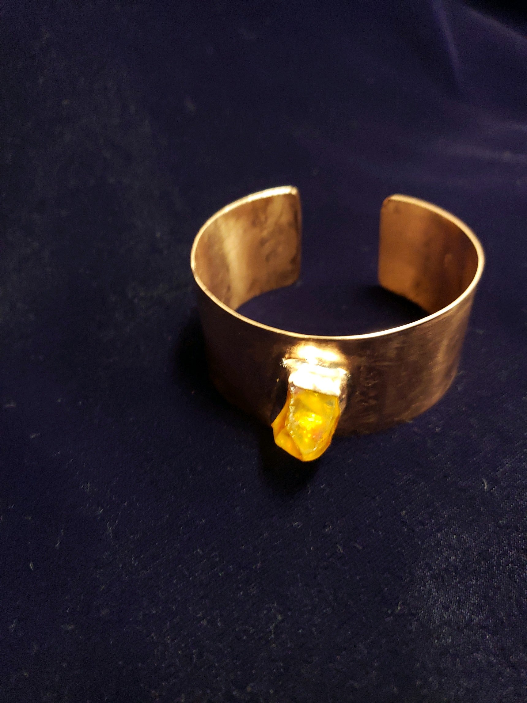 Gold bracelet with a yellow gemstone on a dark background