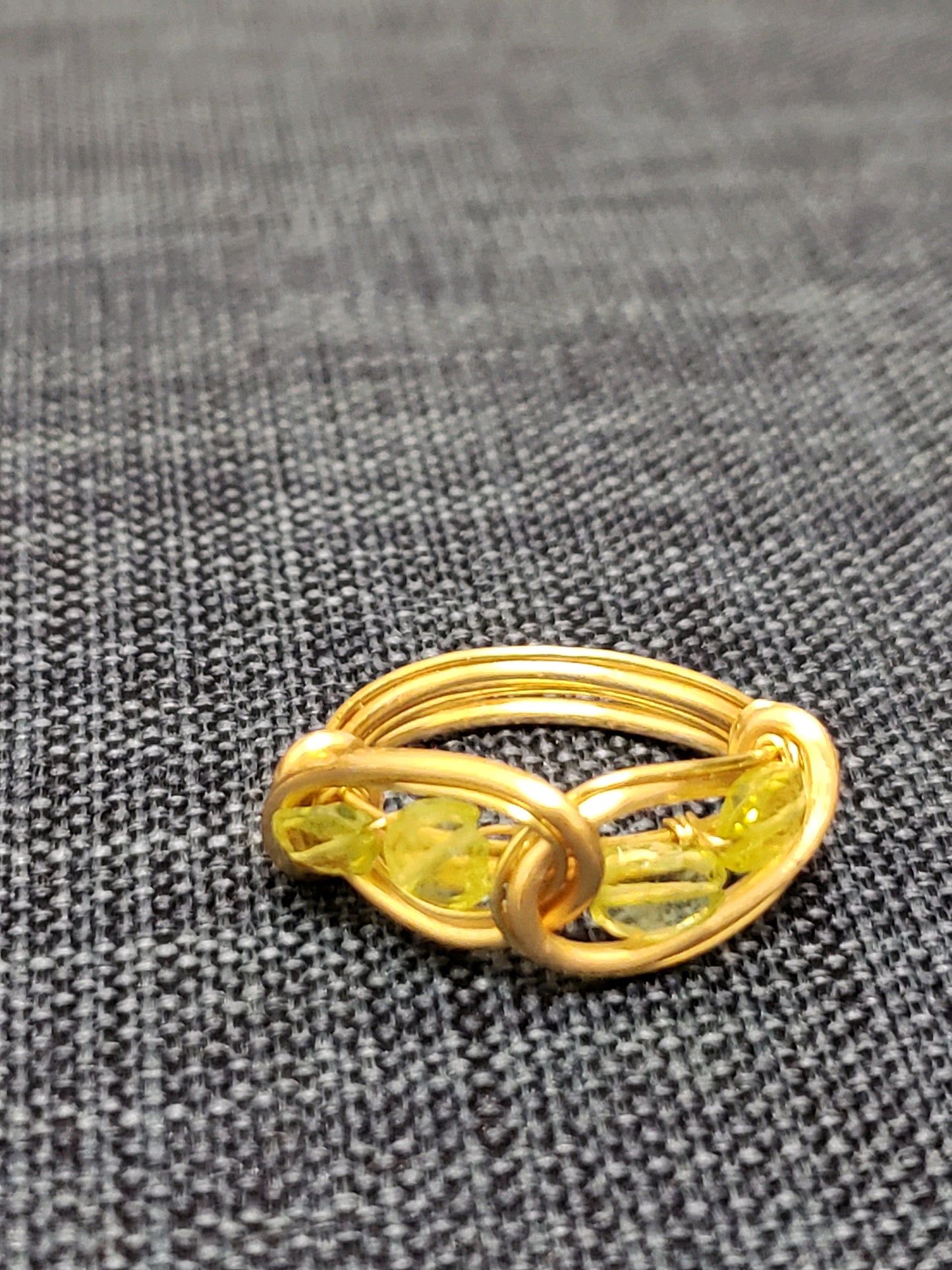 Peridot and Gold ring with a yellow gemstone on a textured gray background