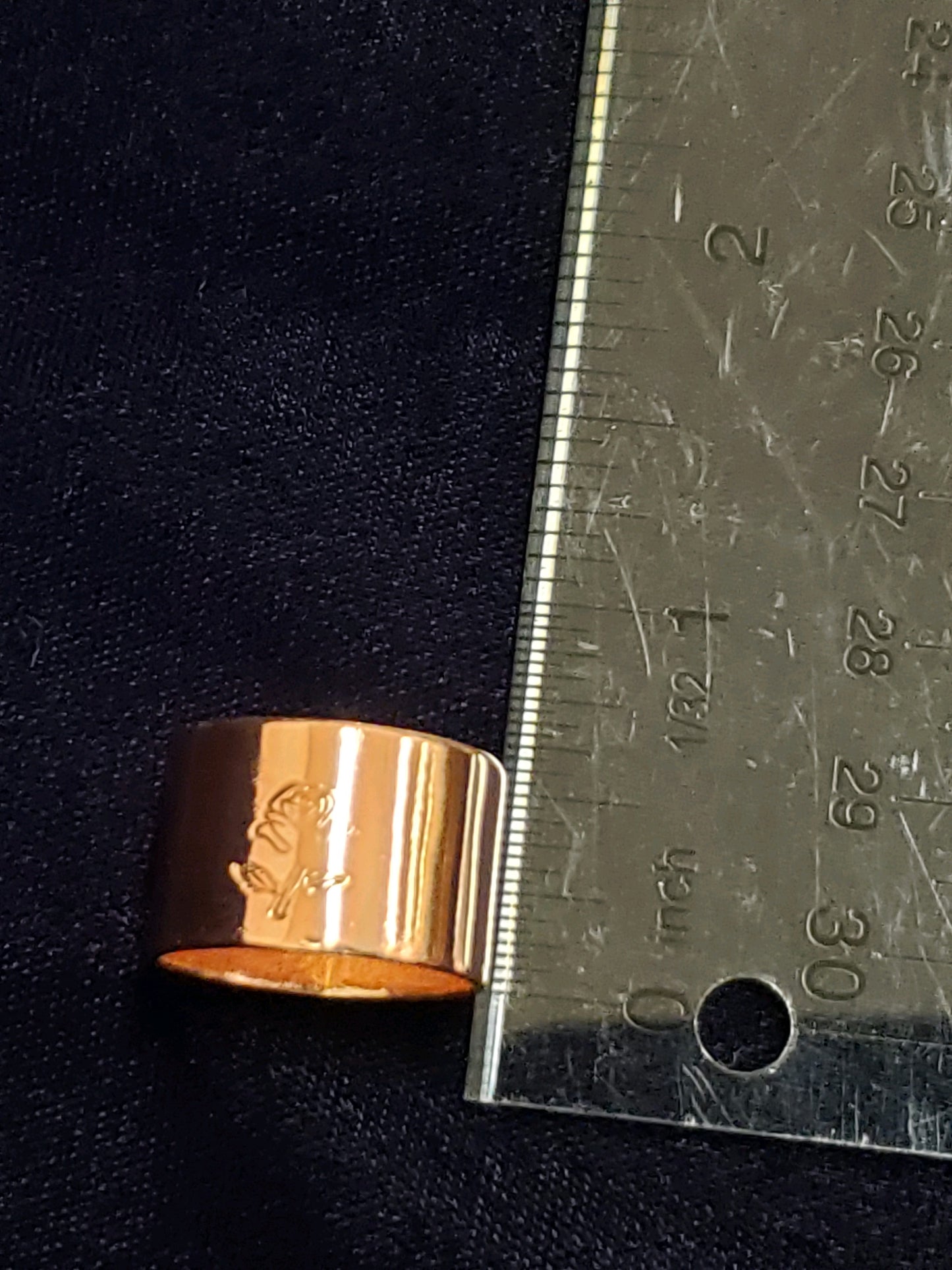 Gold ring next to a ruler on a dark background