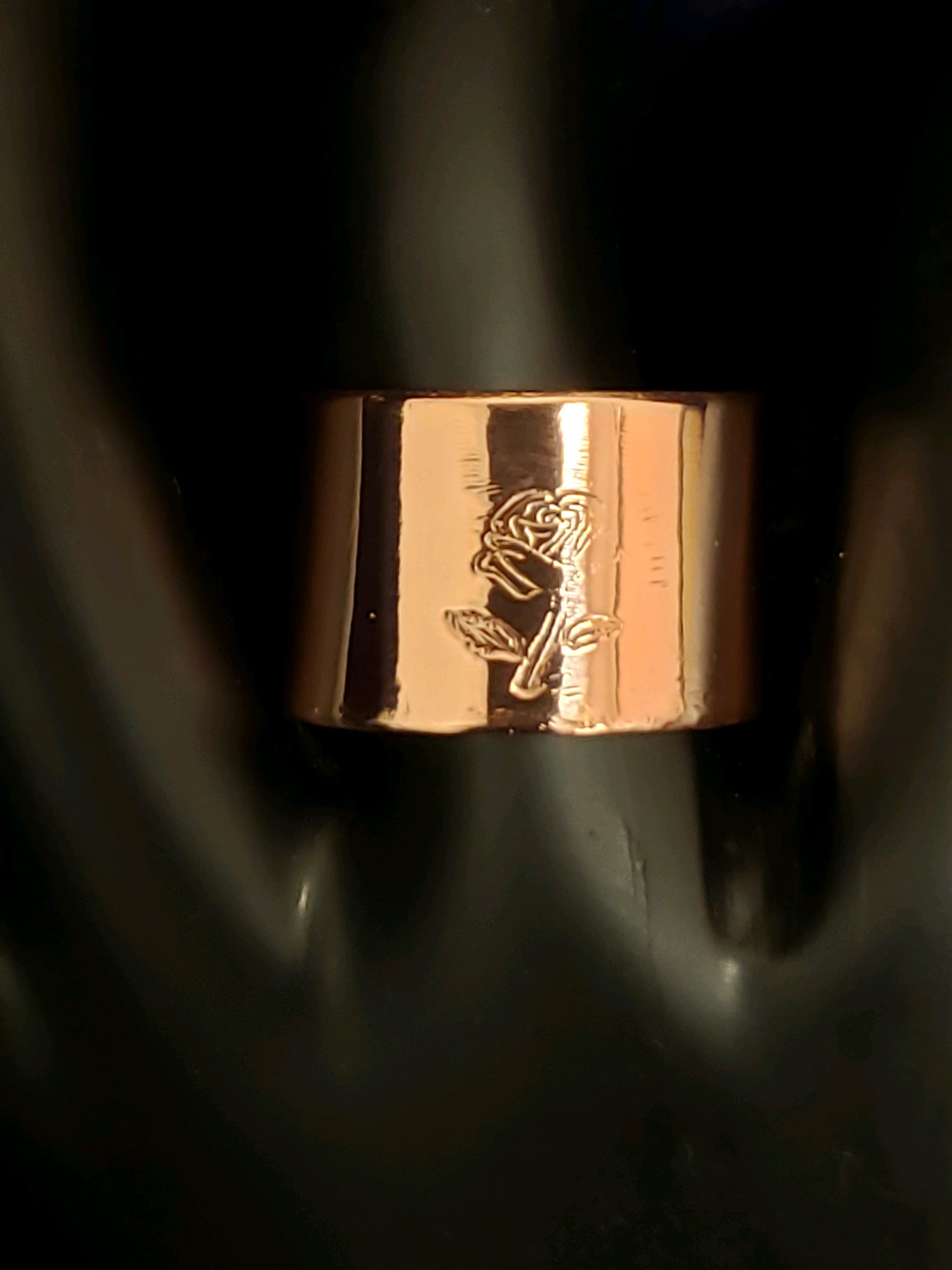 Rose gold ring with engraved design on a dark background