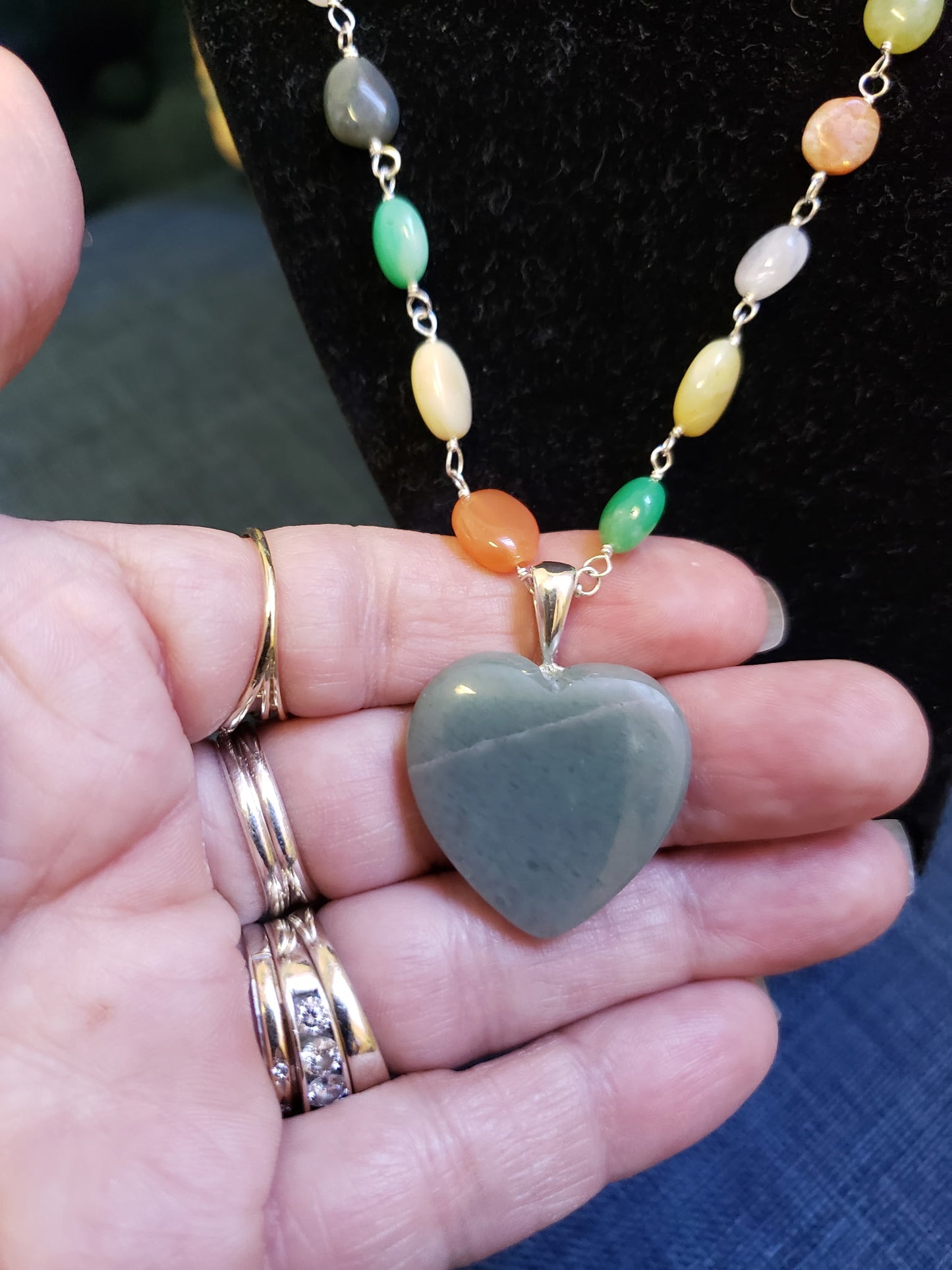 Necklace with a heart-shaped jade pendant held in a hand.