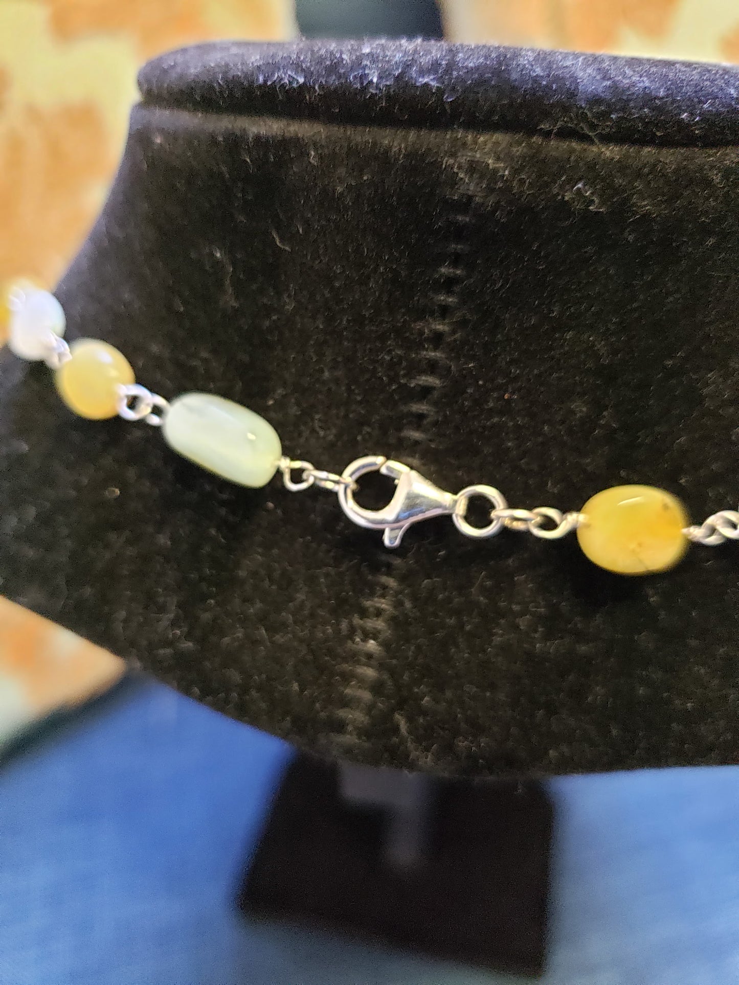 Bracelet with yellow and green beads on a dark velvet stand